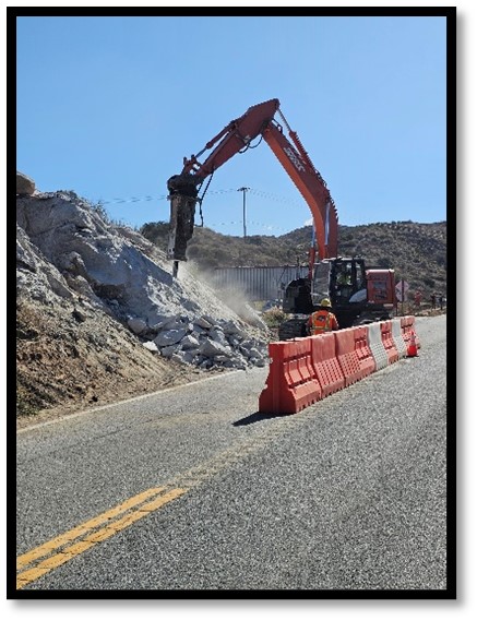 Large excavator equipment working on slope of hillside to make way for new shoulder.