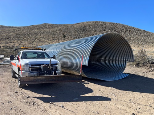 Figure 1: This corrugated steel pipe will become one of two wildlife crossings underneath U.S. 395 as part of the Sonora Junction Shoulders Project. A comparison shot of the new wildlife crossing next to a Caltrans truck, showing the crossing's large size.