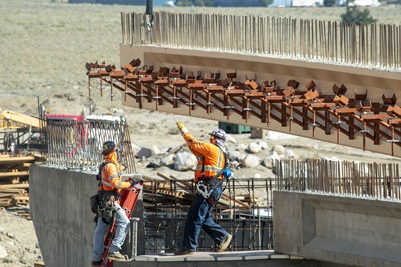 Workers position a bridge girder into place
