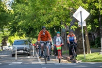 Group of people riding bicycles inside of a protected bike lane on a road in Sacramento