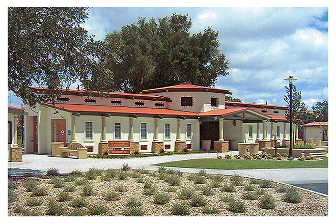 A photo of the Camp Roberts Safety Roadside Rest Area features a facility that houses public restrooms surrounded by tidy water-efficient landscaping, benches, and trash and recycling receptacles.