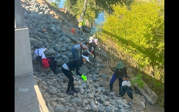 Picture shows a group of six volunteers picking up littler along a rocky riverbed in Sacramento. 