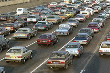 From 1983: color photo of a freeway filled with stopped vehicles as they approach a toll plaza. 