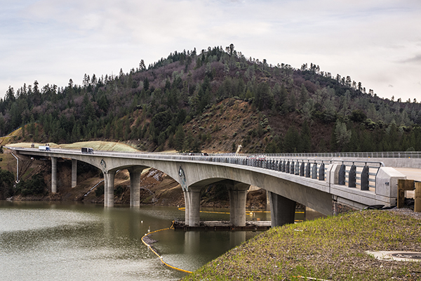 View of a bridge crossing a river that is supported by an alternating pattern of pillars and an arches.