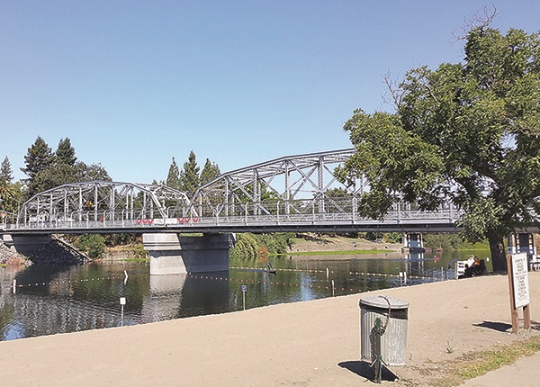 View of bridge spanning a river with to girders arching across the top of the bridge.