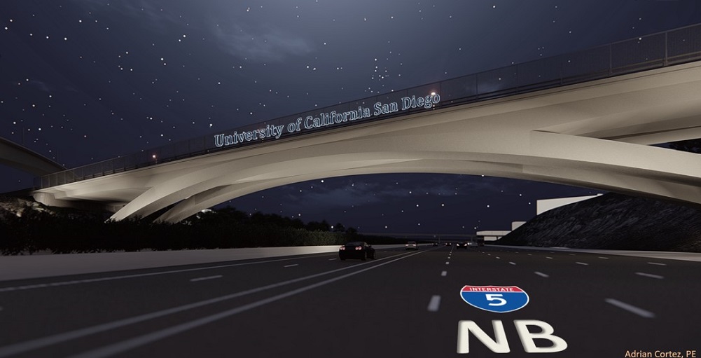 A night-time view of a freeway from the perspective of a car driving underneath a well-lit bridge with the words 'University of California San Diego' on the bridge.