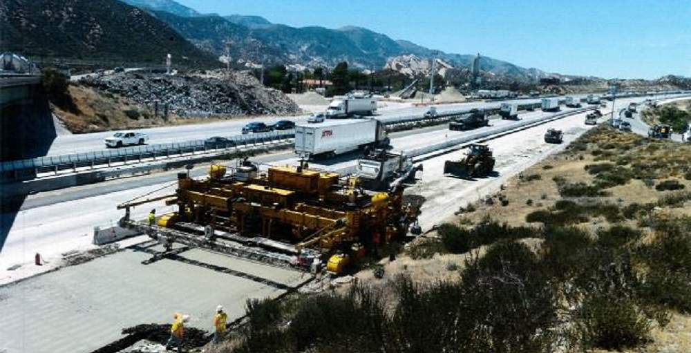 View of a multi-late freeway with construction machinery at work repaving a section.