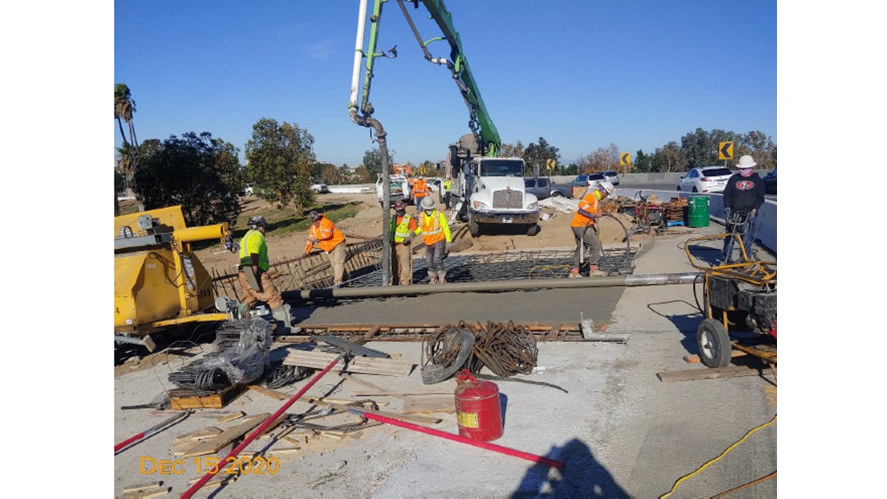 Photo of construction workers, heavy equipment, and fresh asphault