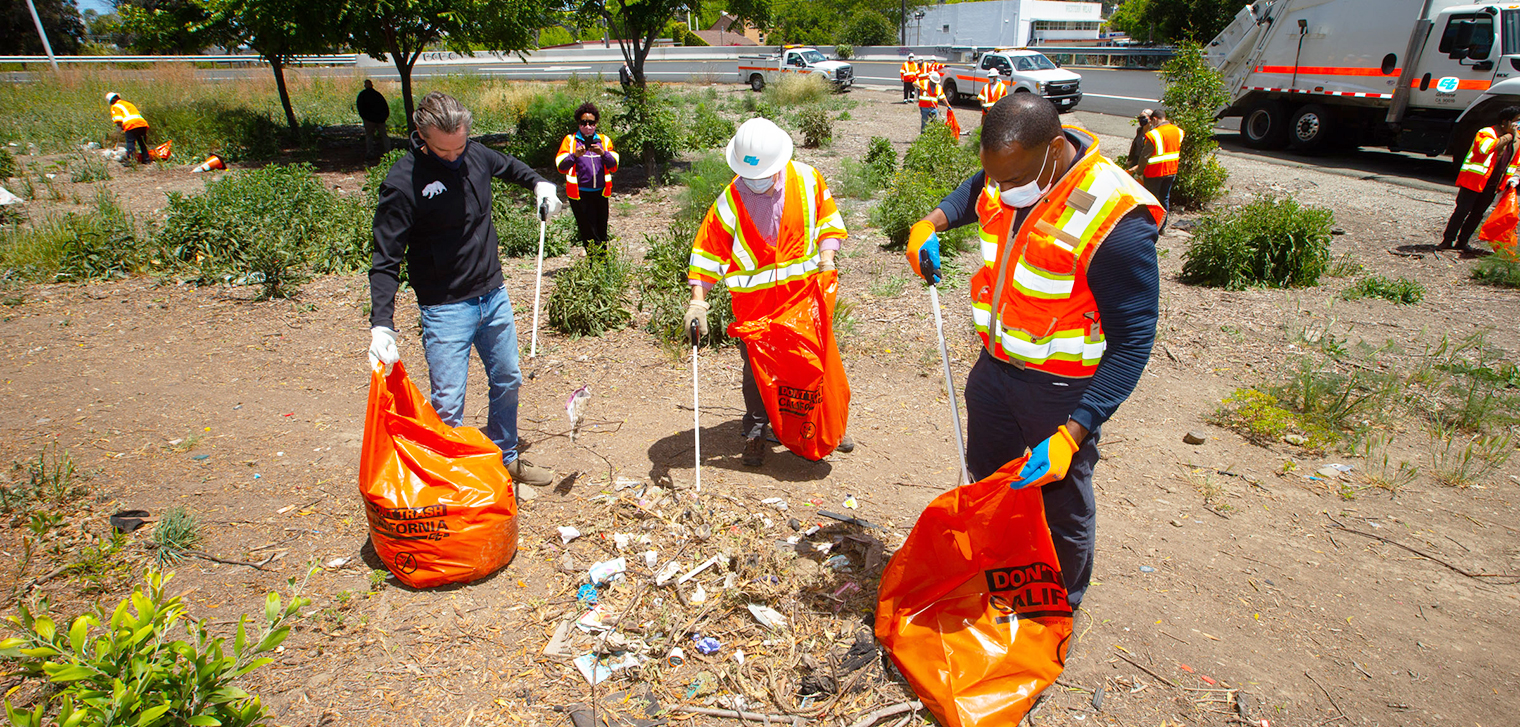 Photo of California Governor, Gavin Newsom and Caltrans Director, Toks Omishakin removing litter from the side of a highway