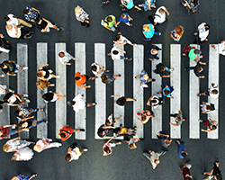 Overhead view of a crosswalk with many pedestrians passing both ways.