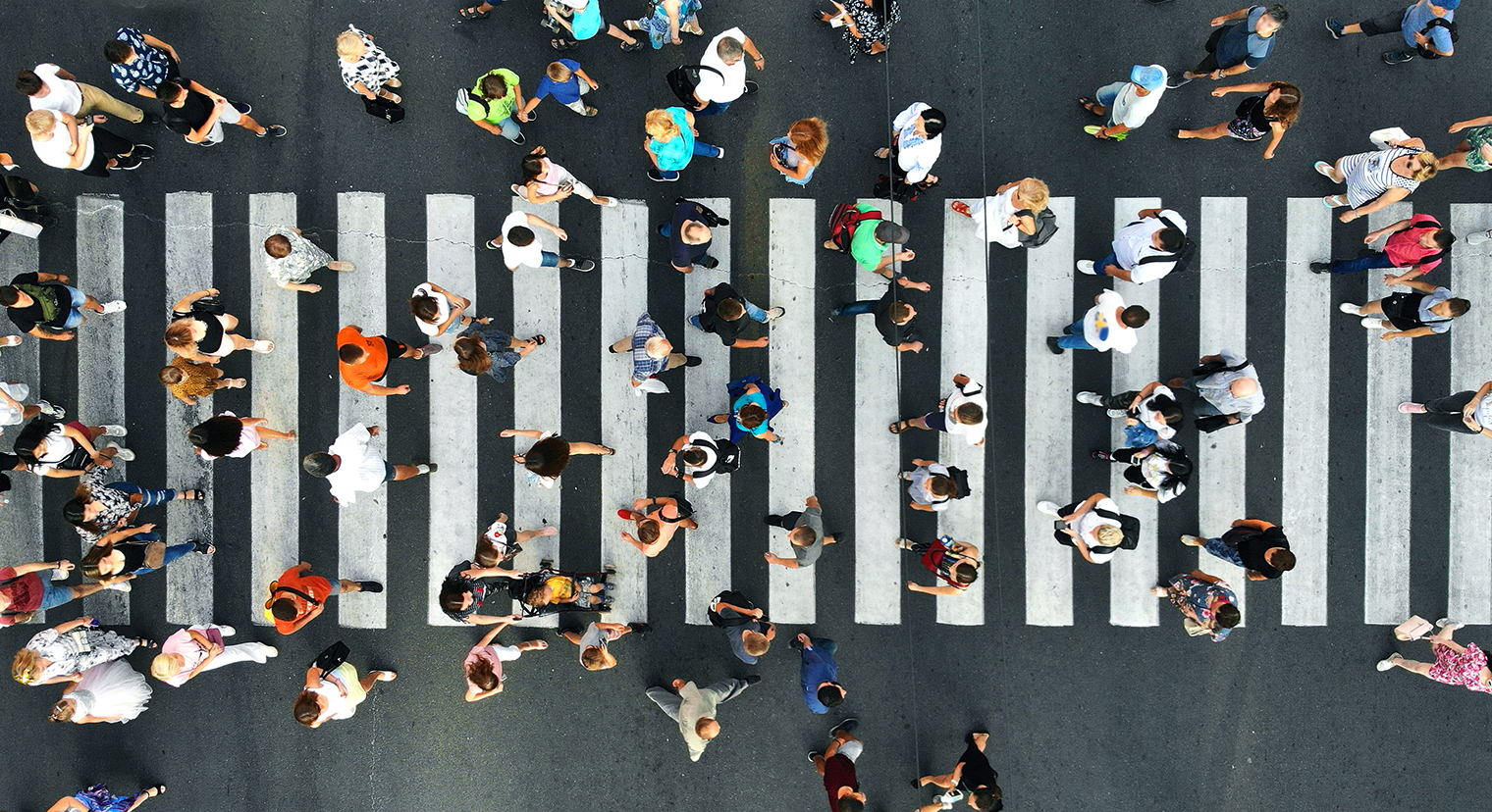 Overhead view of a crosswalk with many pedestrians passing both ways.