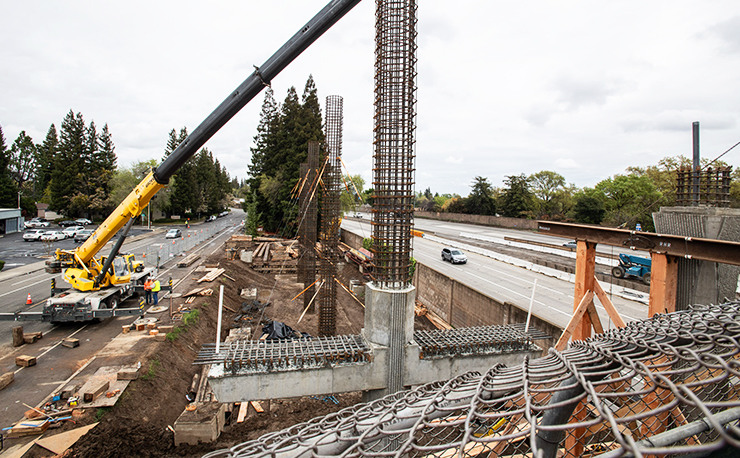Photo showing a construction team and crane along Interstate 5 making enhancements to the corridor.