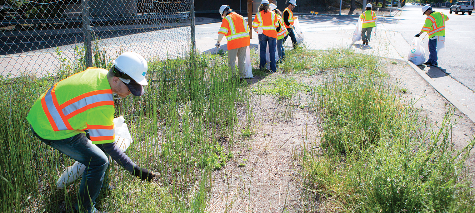 Photo shows a team of Caltrans maintenance workers collecting trash for removal along the roadway