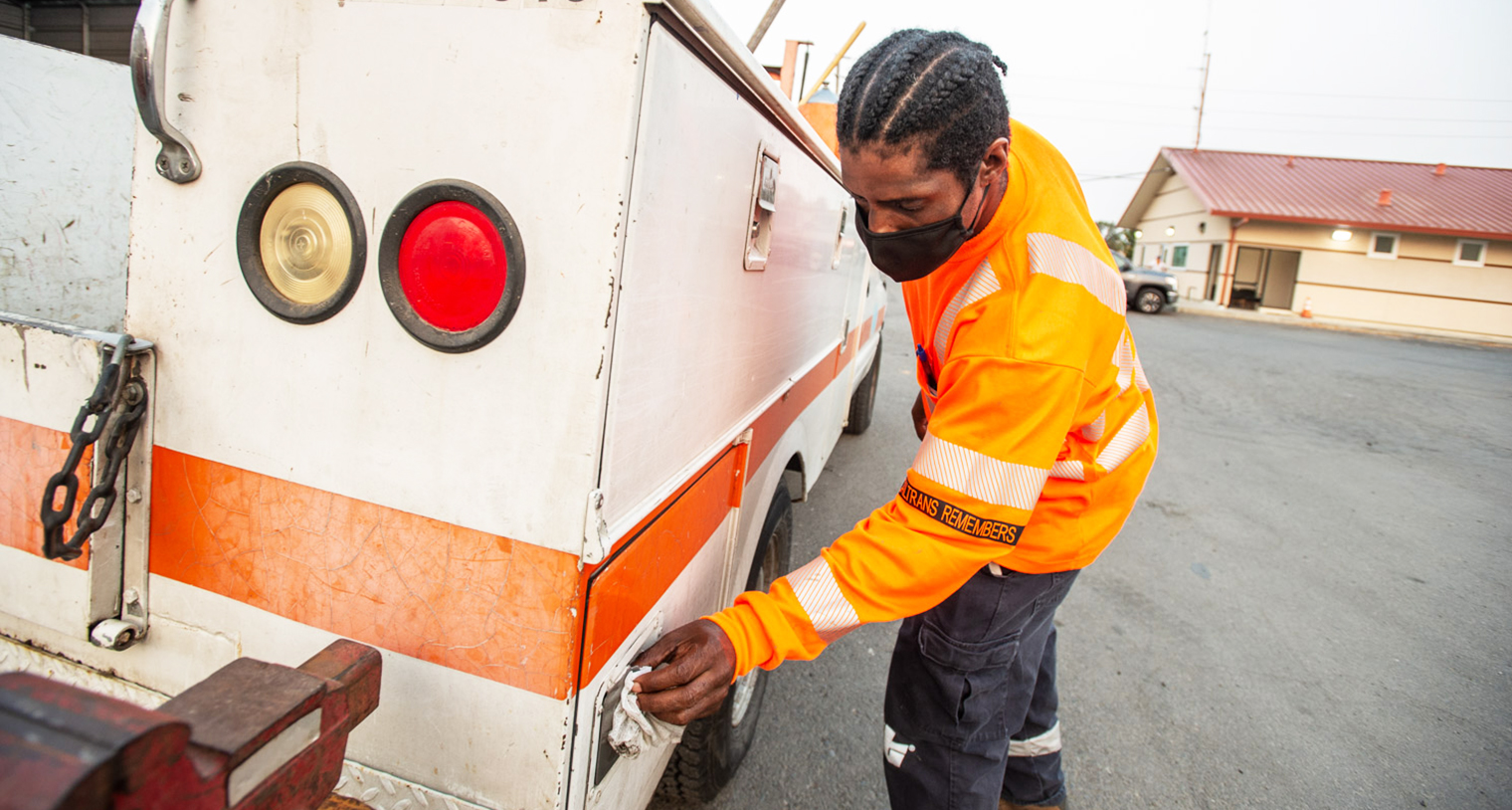 Photo of Caltrans maintenance worker, Shaun Mason cleaning the handles on a Caltrans vehicle with a disinfectant wipe.