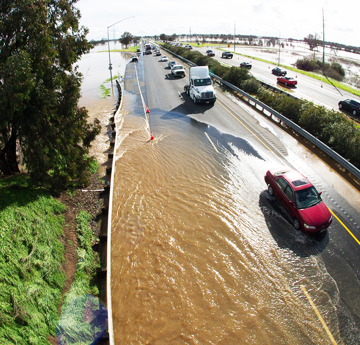 Photo taken from an overpass shows a partially flooded highway with cars trying to pass the water.