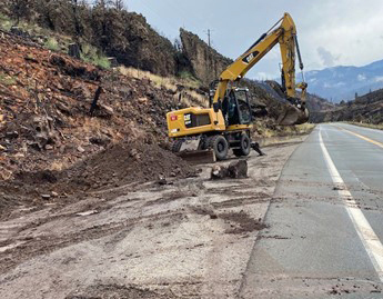 A backhoe on State Route 89 near Markleeville, California (about 30 miles south of Lake Tahoe) on the site of an emergency Caltrans project to clear mudslide debris so that the road can be reopened.