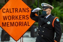Caltrans Honor Guard member salutes in front of an orange "Caltrans Workers Memorial" sign - 31st Annual Caltrans Workers Memorial Ceremony April 29, 2021 - California State Capitol, Sacramento