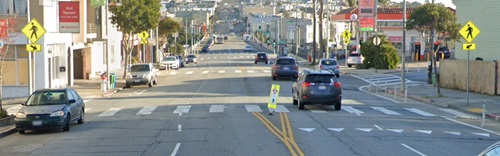 Image of roadway with in-street pedestrian crossing markings and signs to remind road users of laws regarding right-of-way at an unsignalized pedestrian crossing