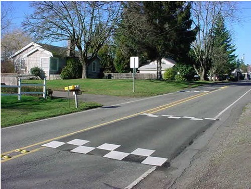 Image of an offset speed table that is a speed tale spit in half down the street centerline with longitudinal separation between the two halves, which allows emergency vehicles to pass through with minimal delay