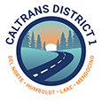 Caltrans District 1 shield. Humboldt; Del Norte; Lake; Mendocino. The sun sets over a road that winds from the foreground to the background. Mountains line each side.